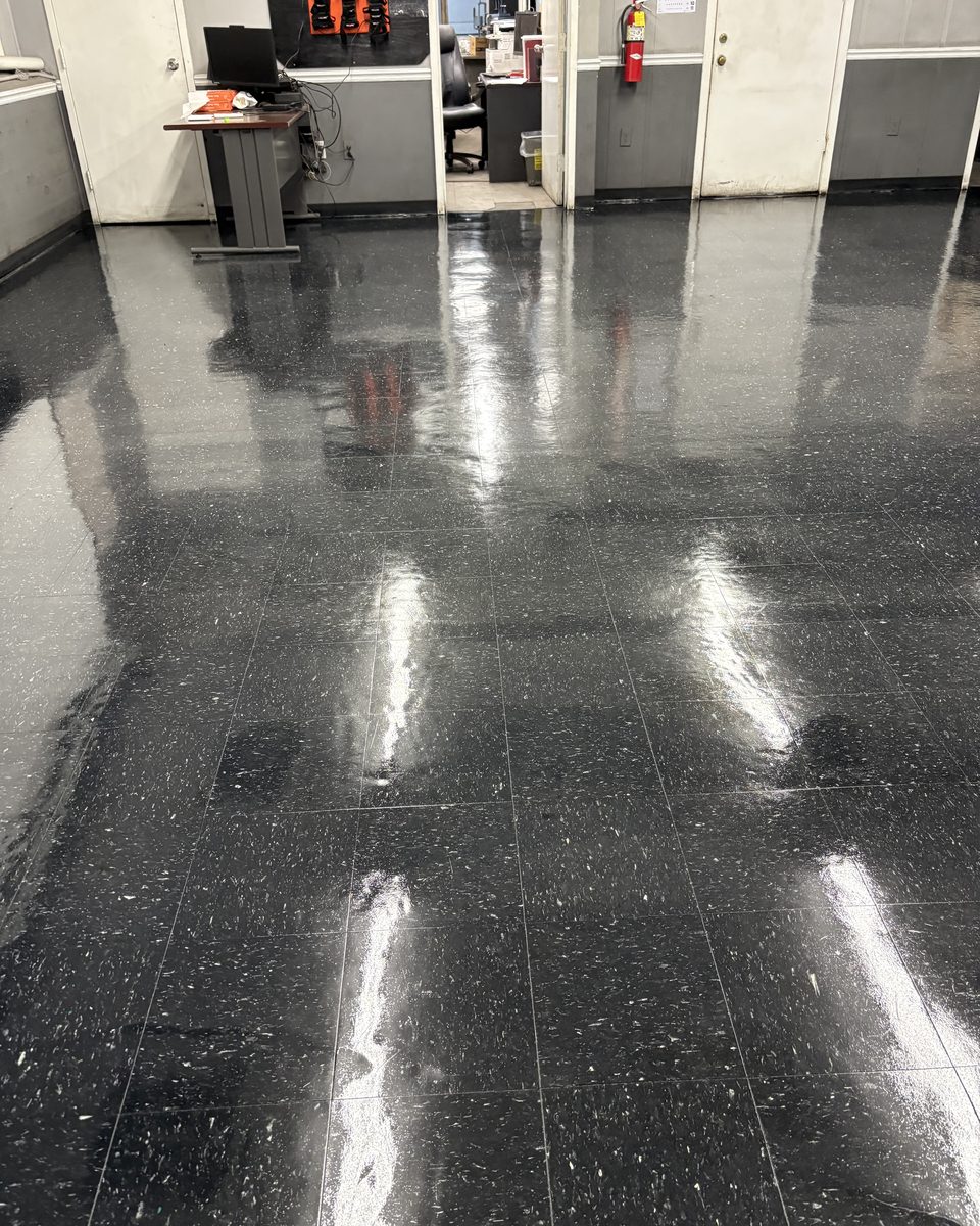 Dark speckled VCT floor with a deep gloss in an office hallway